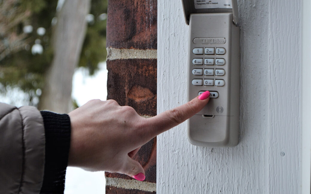 Close up of a woman's hand pressing a button on a garage door opener.