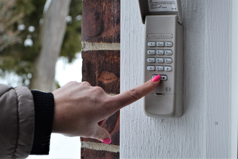 Close up of a woman's hand pressing a button on a garage door opener.