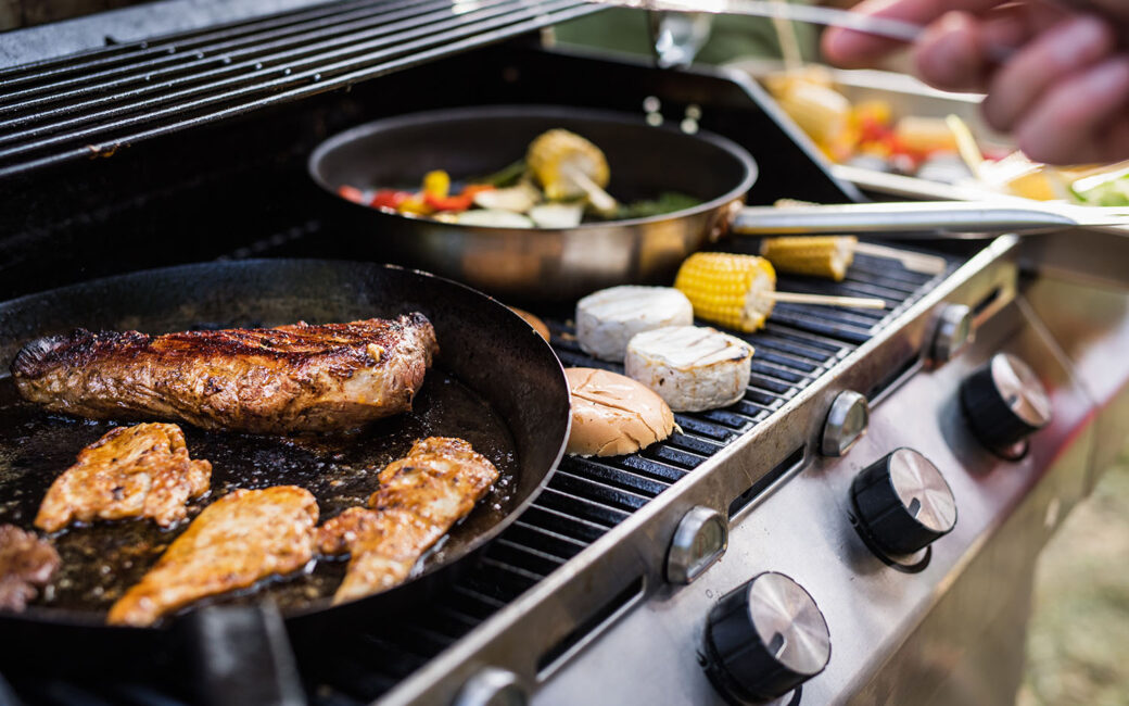 Meat, sausages and cheese on the grill. Family celebration outside in the backyard. Big garden party.